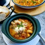 A green soup dish filled with bully beef minestrone.