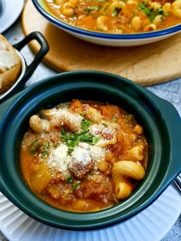A green soup dish filled with bully beef minestrone.