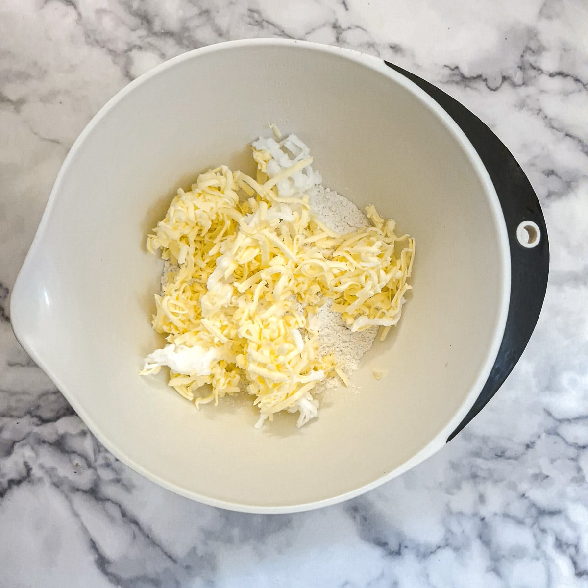 Grated lard and butter in a mixing bowl with flour.