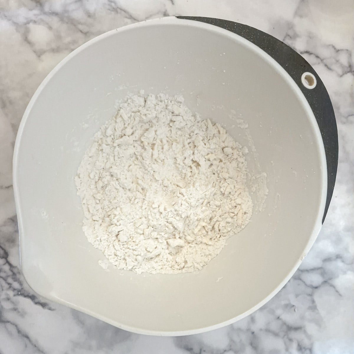 Grated lard and butter combined with flour in a mixing bowl.
