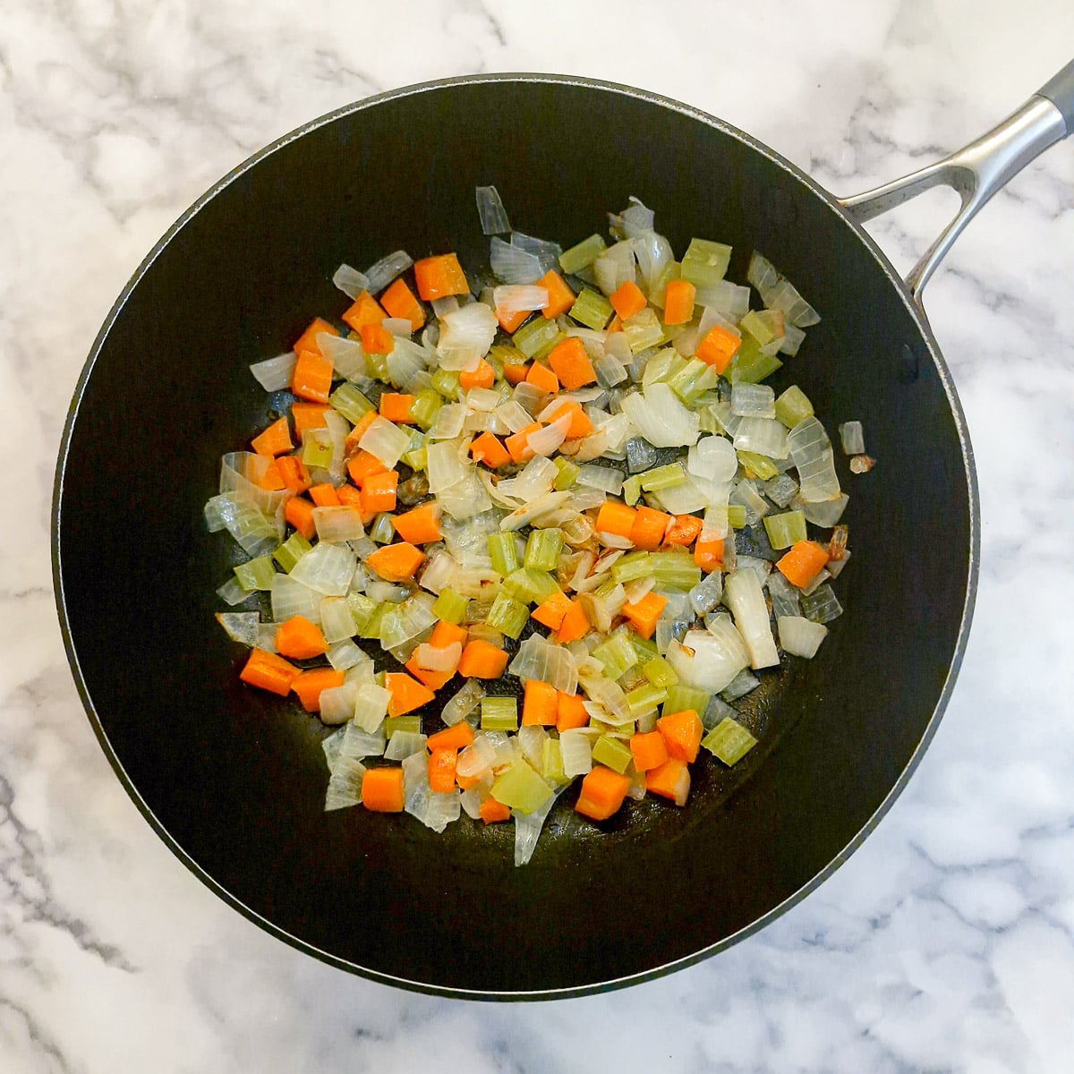 A mirepoix of carrots,,
celery and onions in a frying pan.