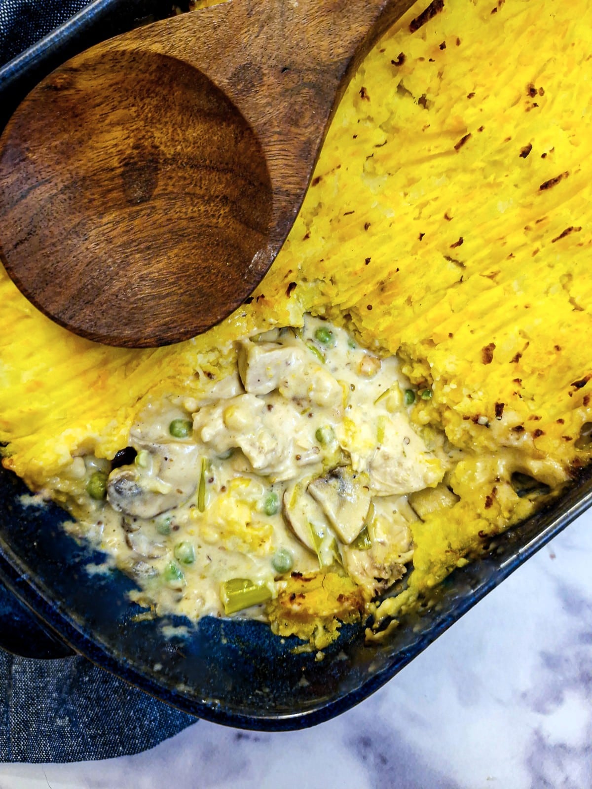 Overhead shot of chicken shepherd's pie with one corner of the potato removed to show the filling inside.