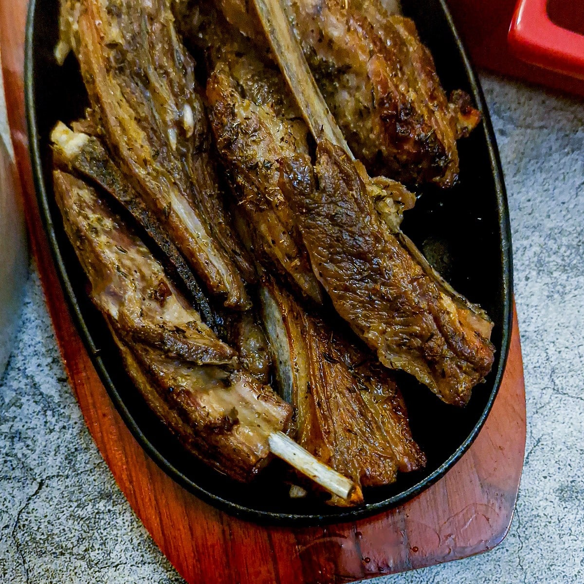 A dish of lemon and herb lamb ribs on a wooden platter.