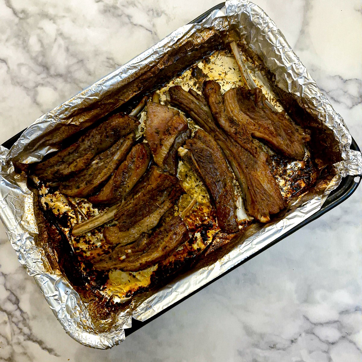 A baking dish with browned lamb ribs.