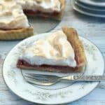 A slice of raspberry meringue pie on a blue-patterned plate.