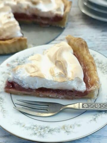 A slice of raspberry meringue pie on a blue-patterned plate.