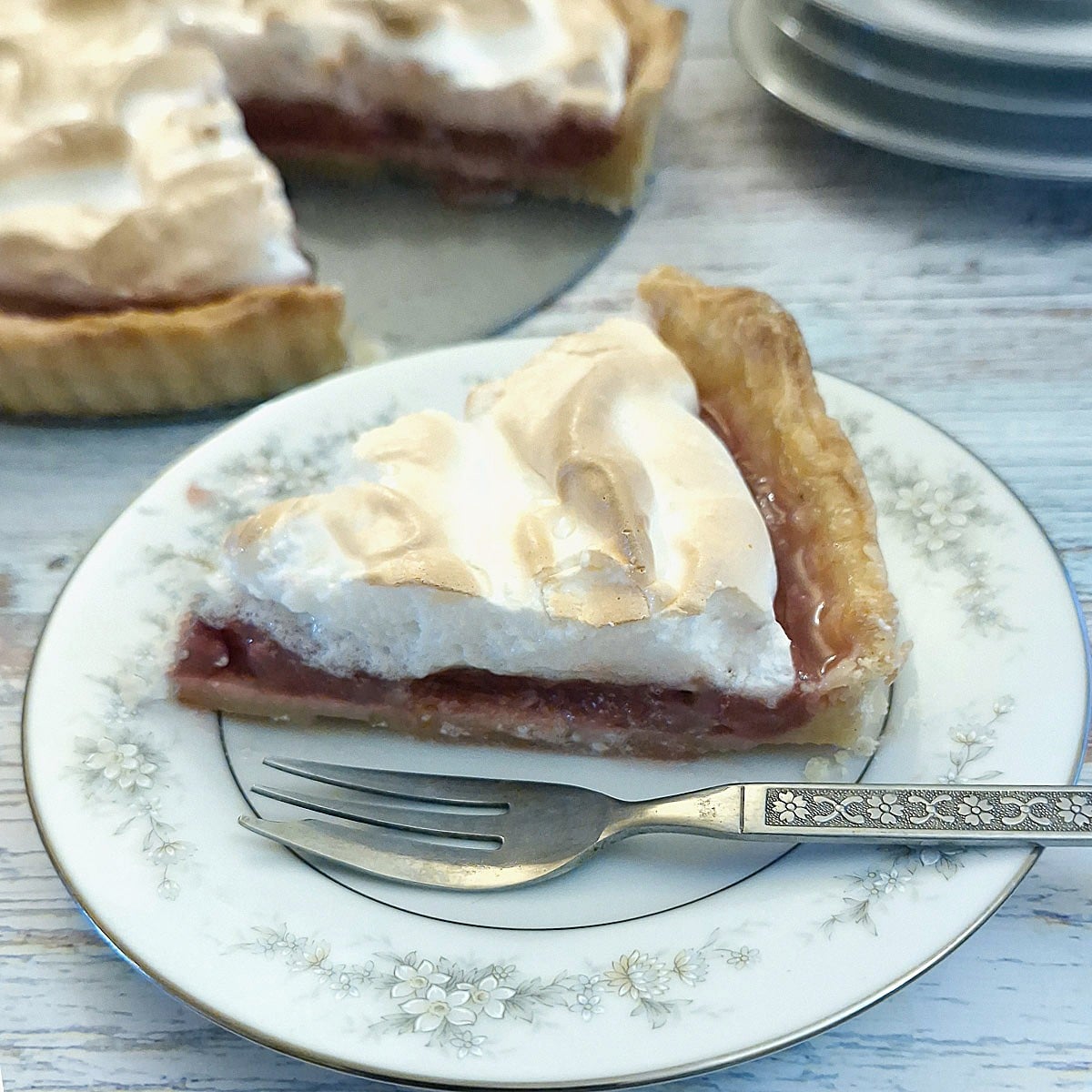 A slice of raspberry meringue pie on a blue-patterned plate.