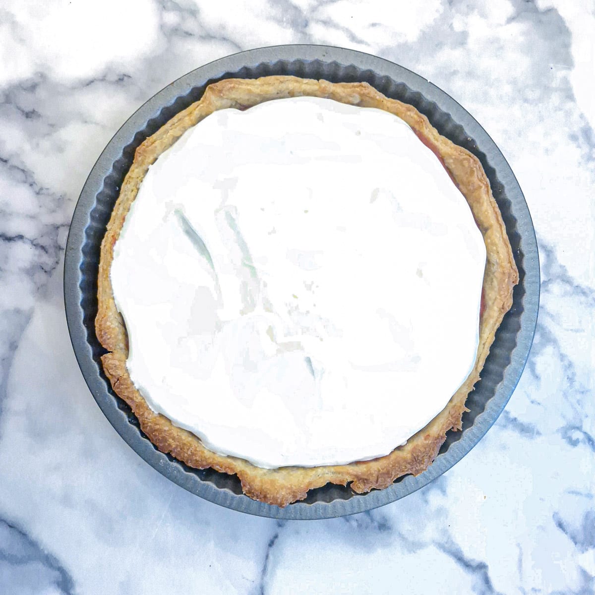Meringue spread over the raspberry curd in a pastry shell.