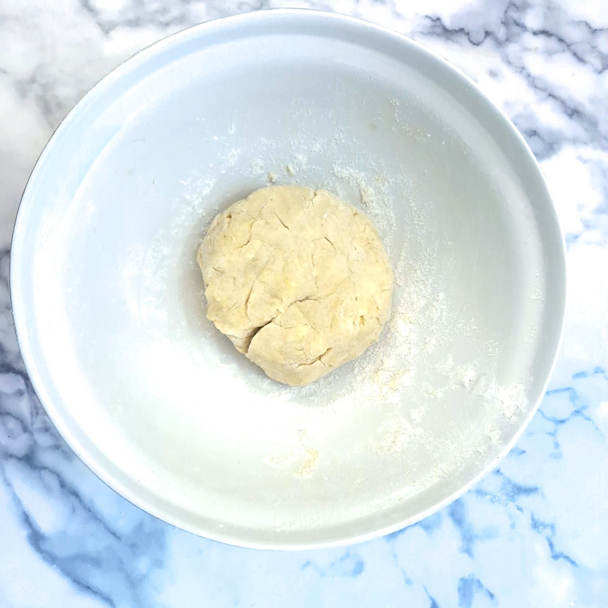 A ball of pastry in a mixing bowl.