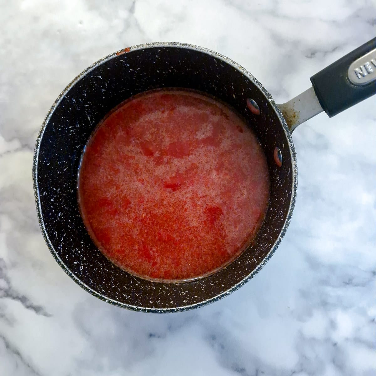 Raspberry pulp in a saucepan with sugar and lemon juice.