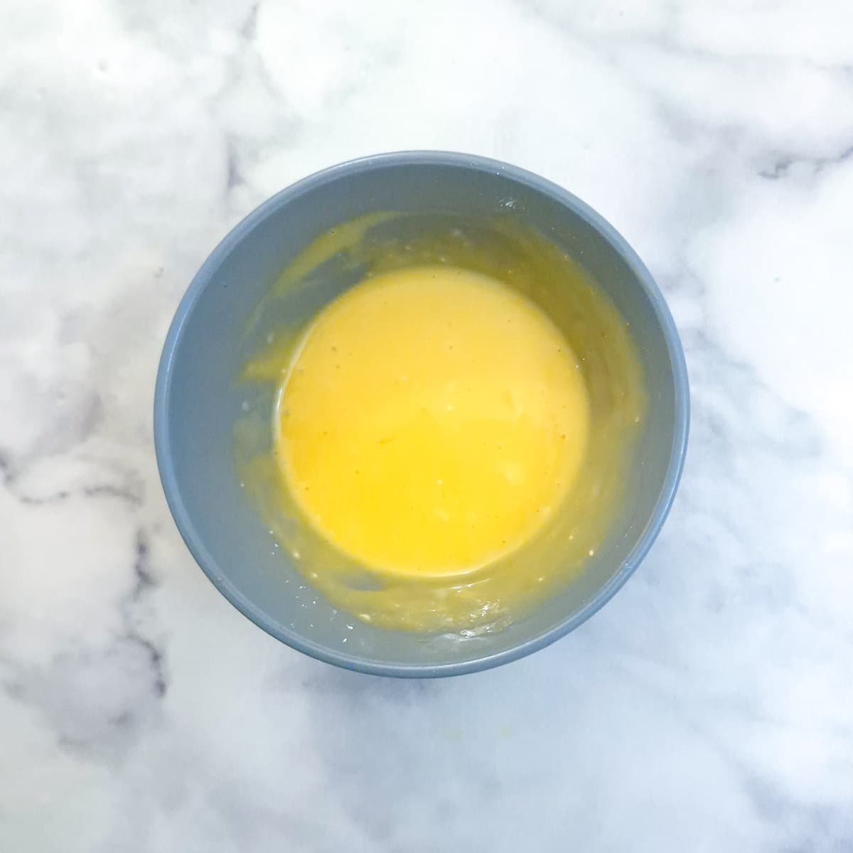 Egg yolks and cornflour combined in a small blue bowl.