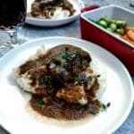 A piece of slow-braised beef cheek on a pile of mashed potatoes, with gravy.