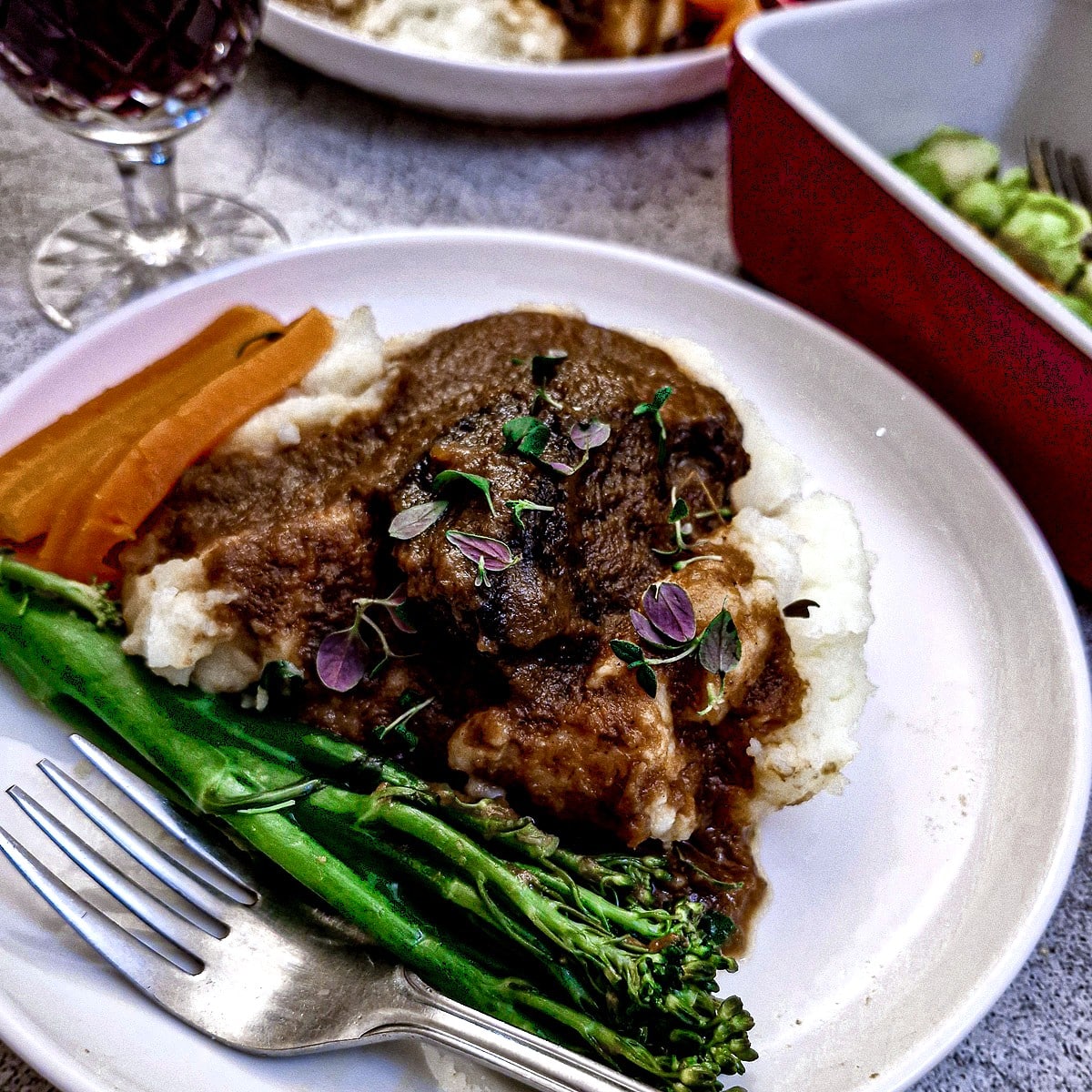 Slow-braised beef cheek on mashed potatoes with steamed broccoli and carrots.