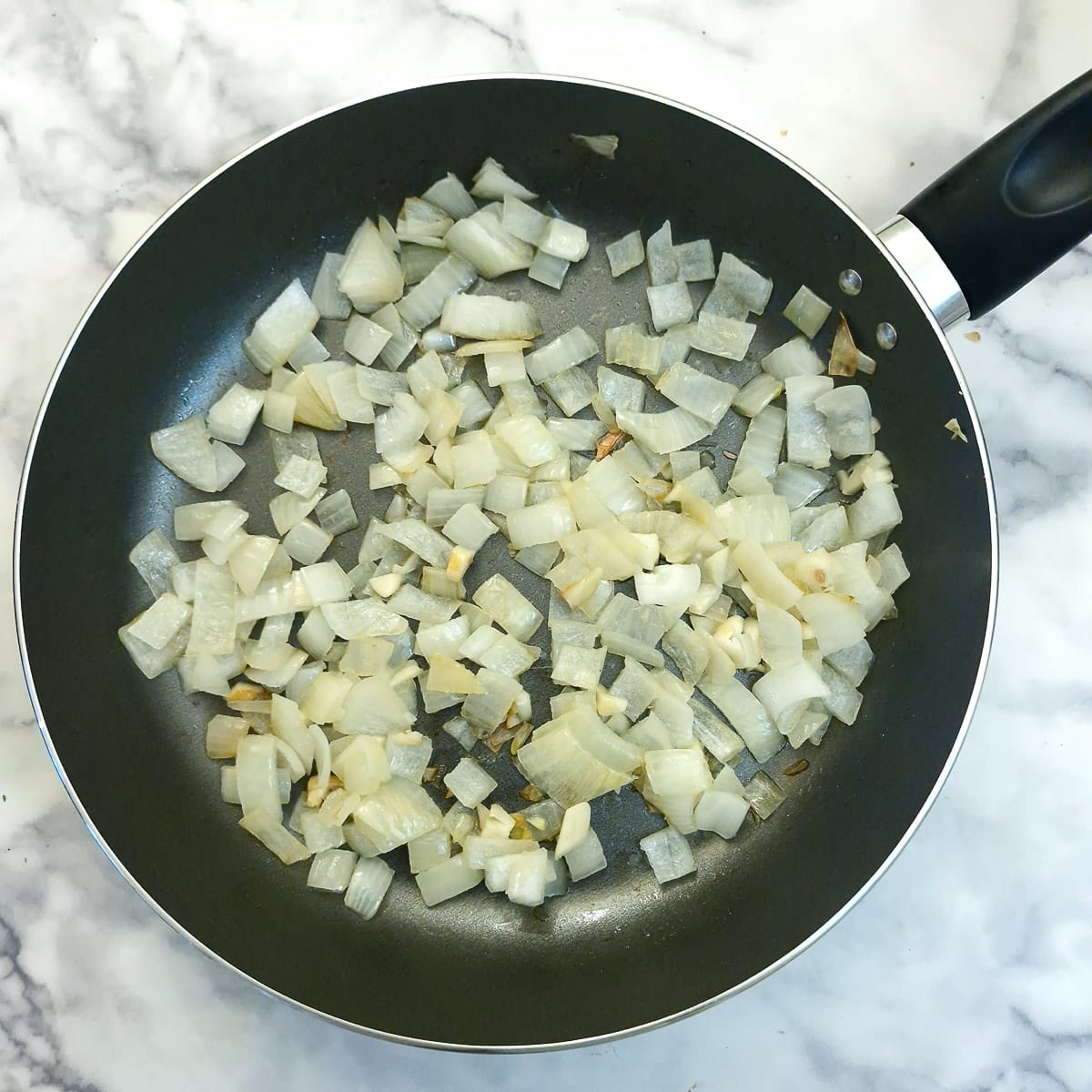 Onions softening in a frying pan.