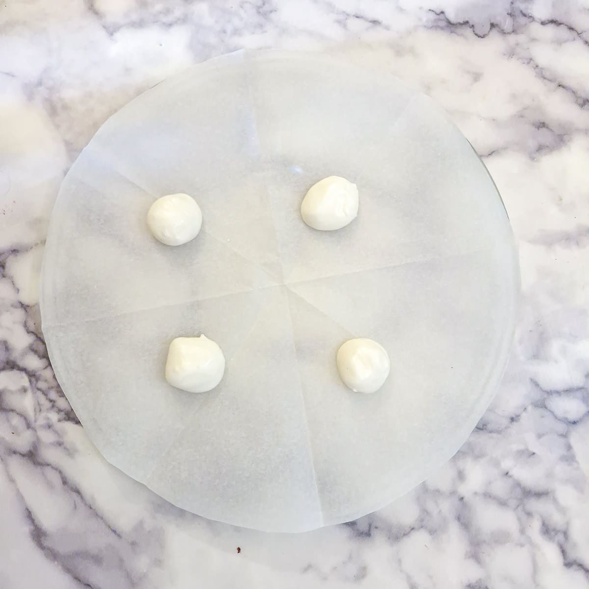 4 balls of meringue dough on a microwave plate.