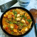 A black serving dish of Thai prawn and monkfish curry.