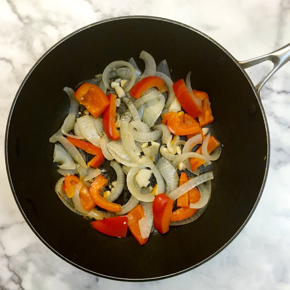Onions, red pepper and garlic frying in a pan,