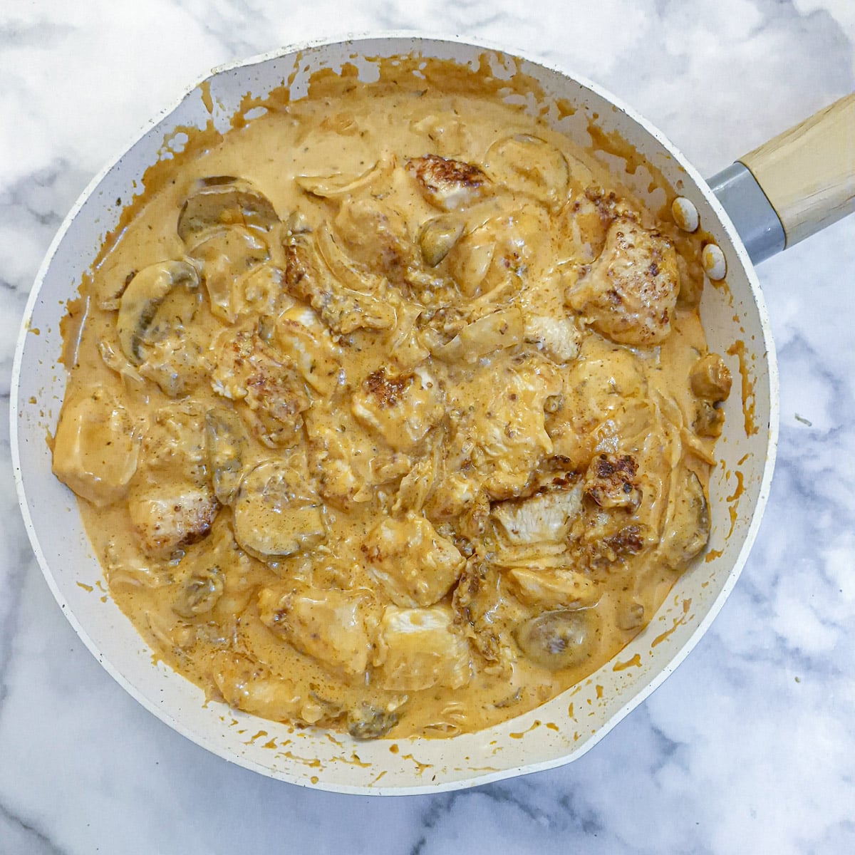 Fully cooked mushroom chicken in mustard sauce in a pan.