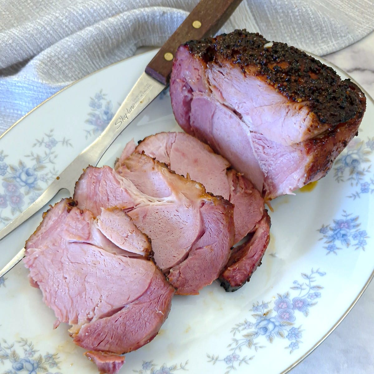 Sliced honey roasted gammon on a white serving platter.