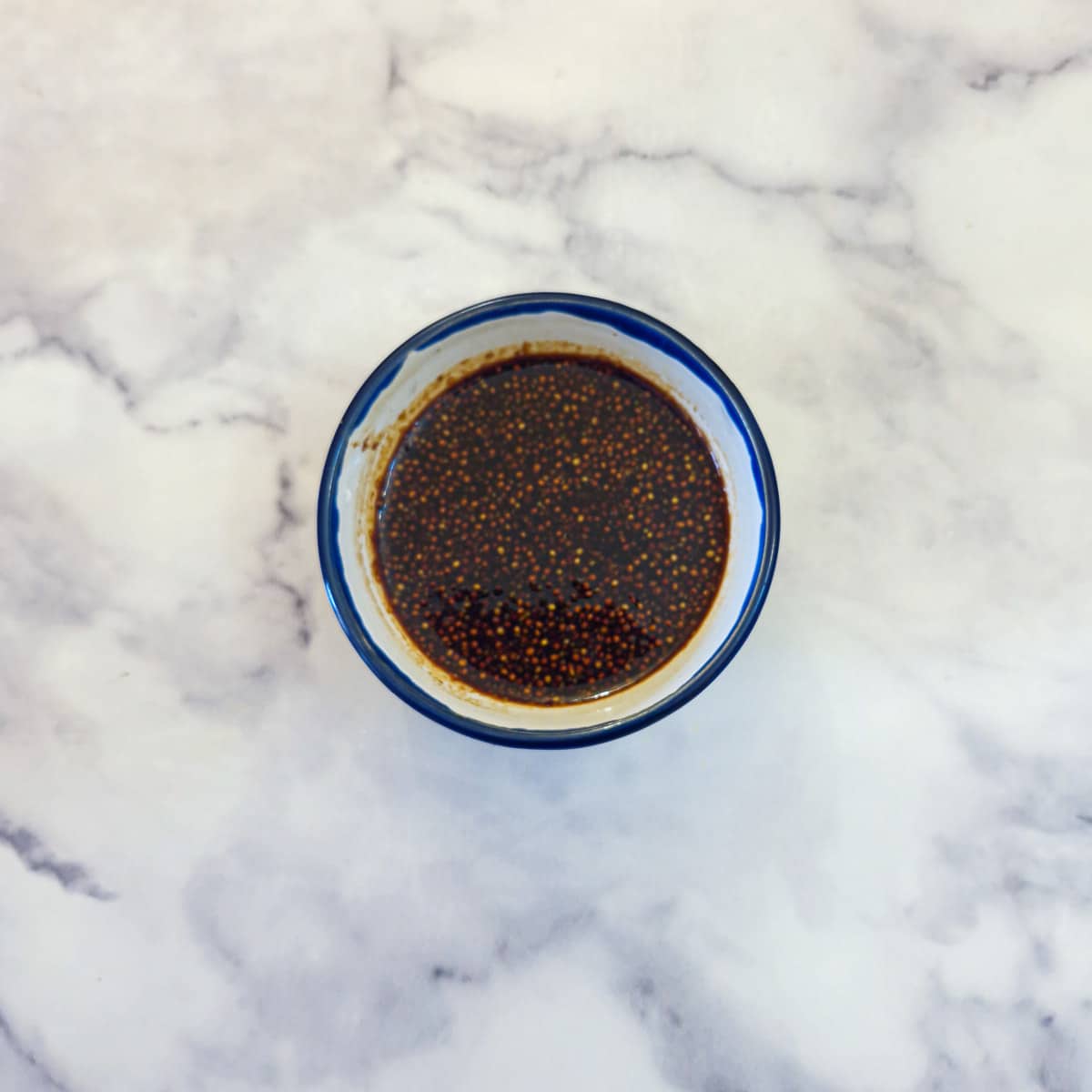 A small blue-rimmed white bowl containing a honey mustard glaze.