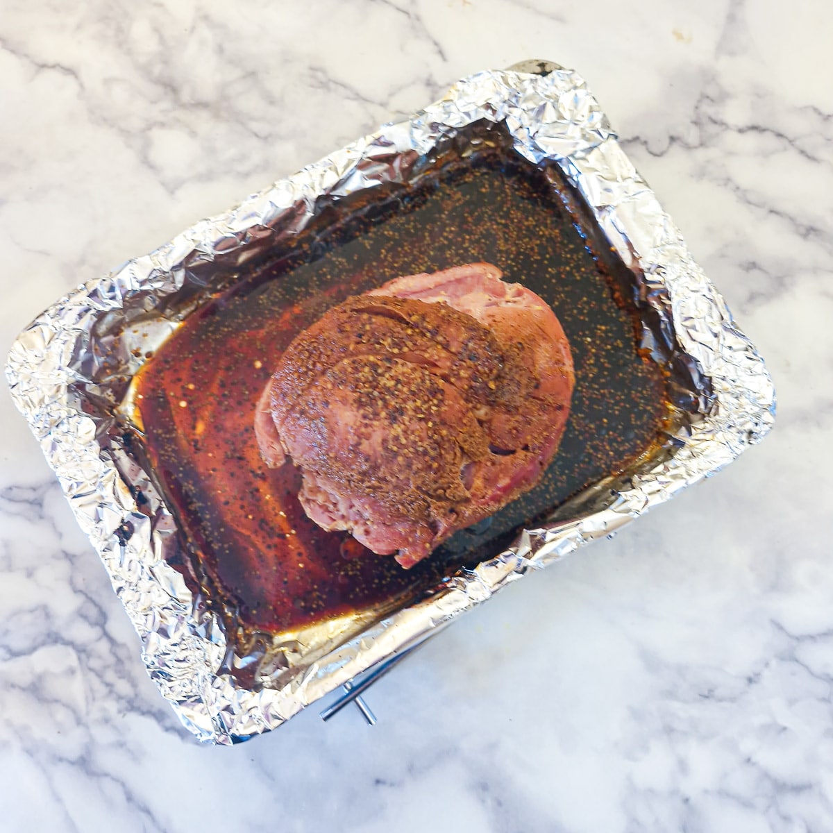 Cooked gammon in a foil-lined roasting dish.