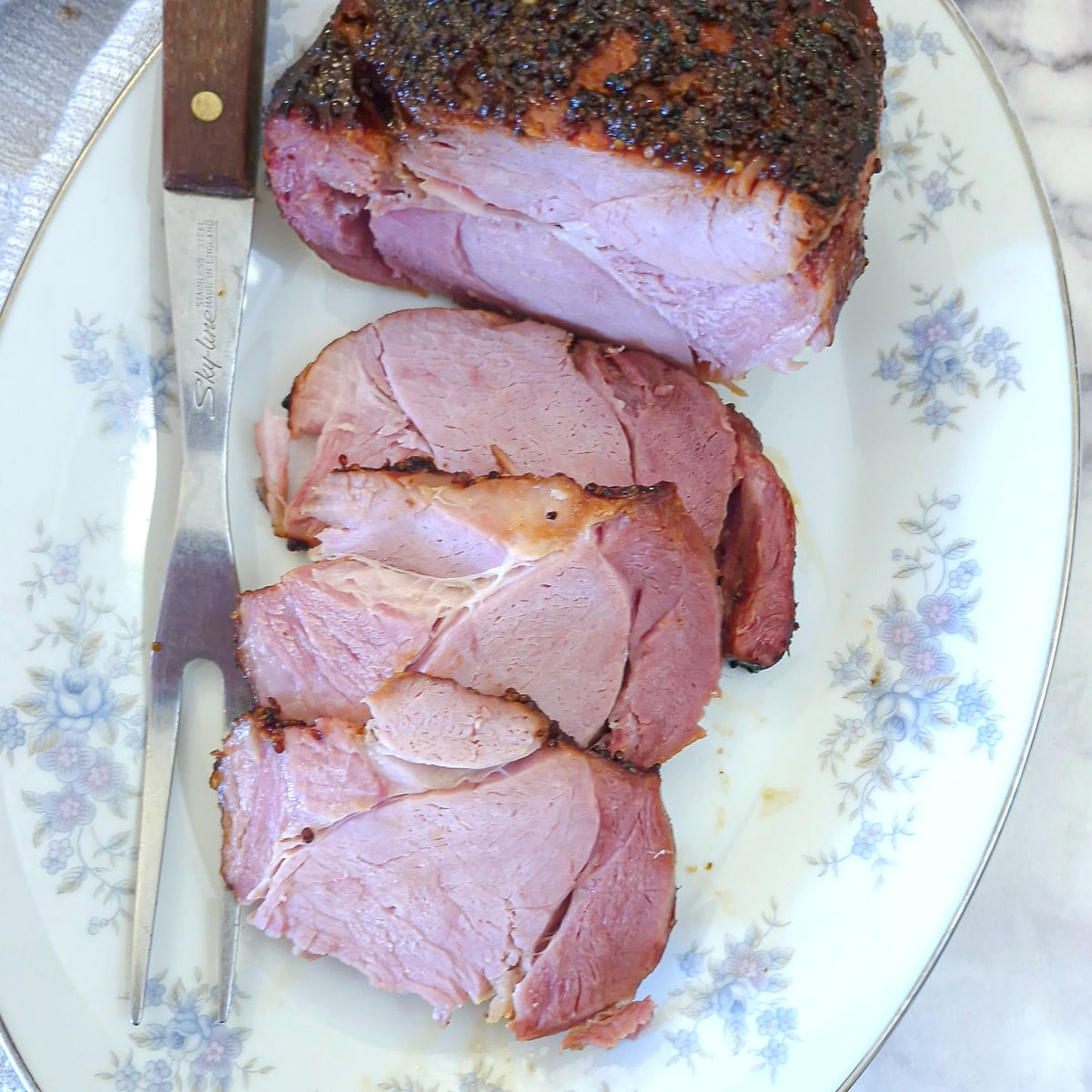 Sliced honey roasted gammon on a white serving platter.