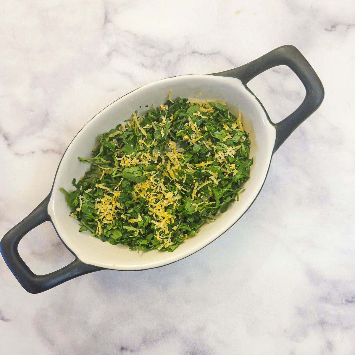 A small dish of chopped parsley and lemon zest.