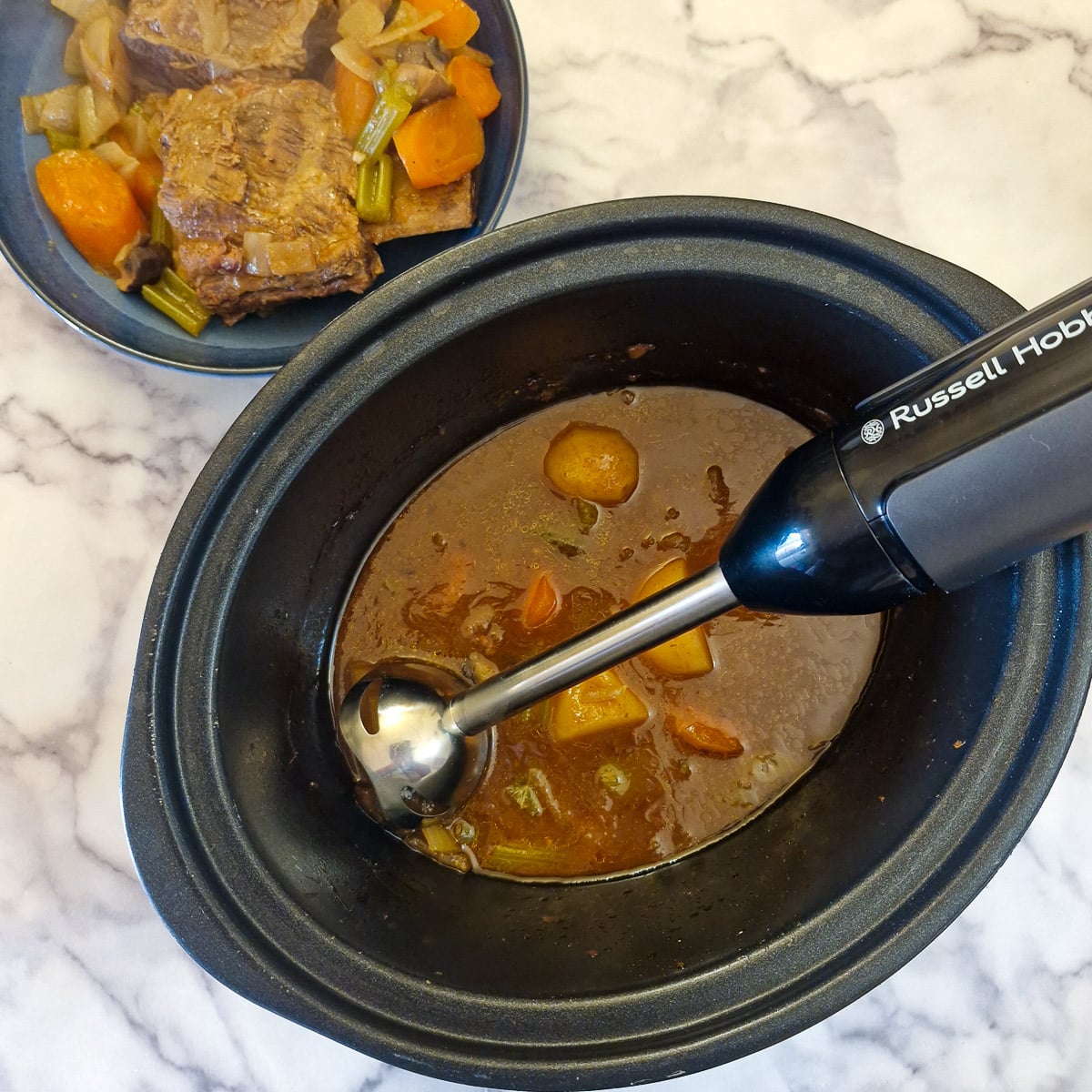 Gravy being blended with a stick blender.