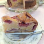 A slice of strawberry mascarpone cake on a blue patterned plate with a cake fork.