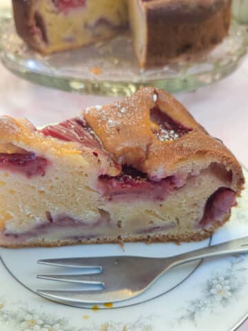 A slice of strawberry mascarpone cake on a blue patterned plate with a cake fork.
