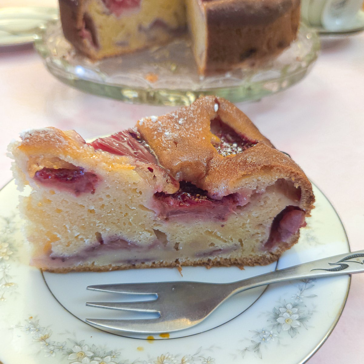 A slice of strawberry mascarpone cake on a blue patterned plate with a cake fork.