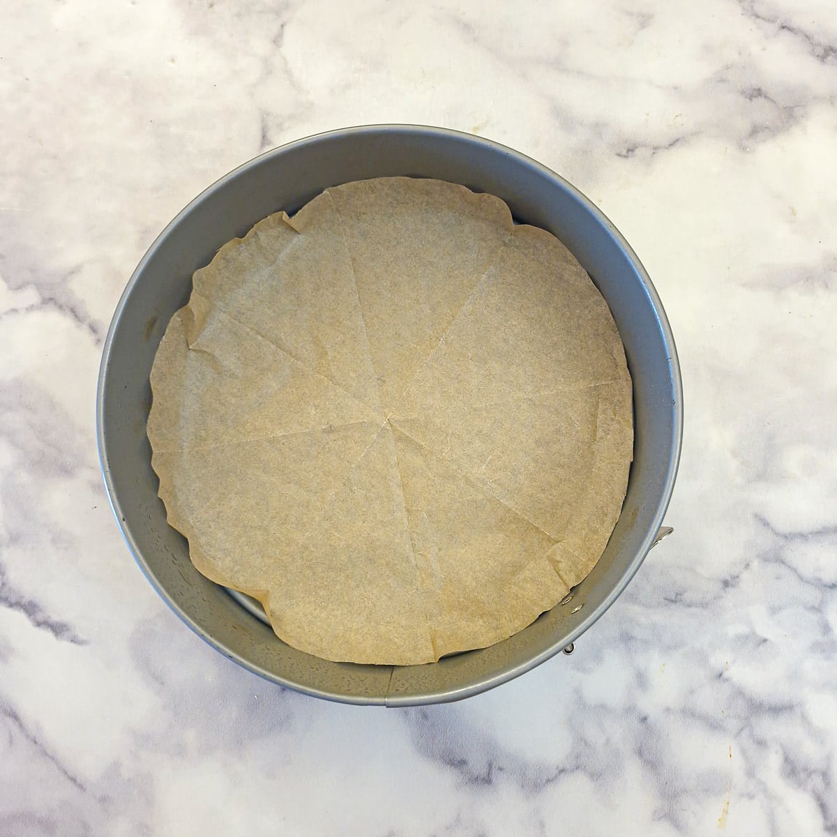 An 8-inch diameter springform cake pan lined with a circle of baking parchment.