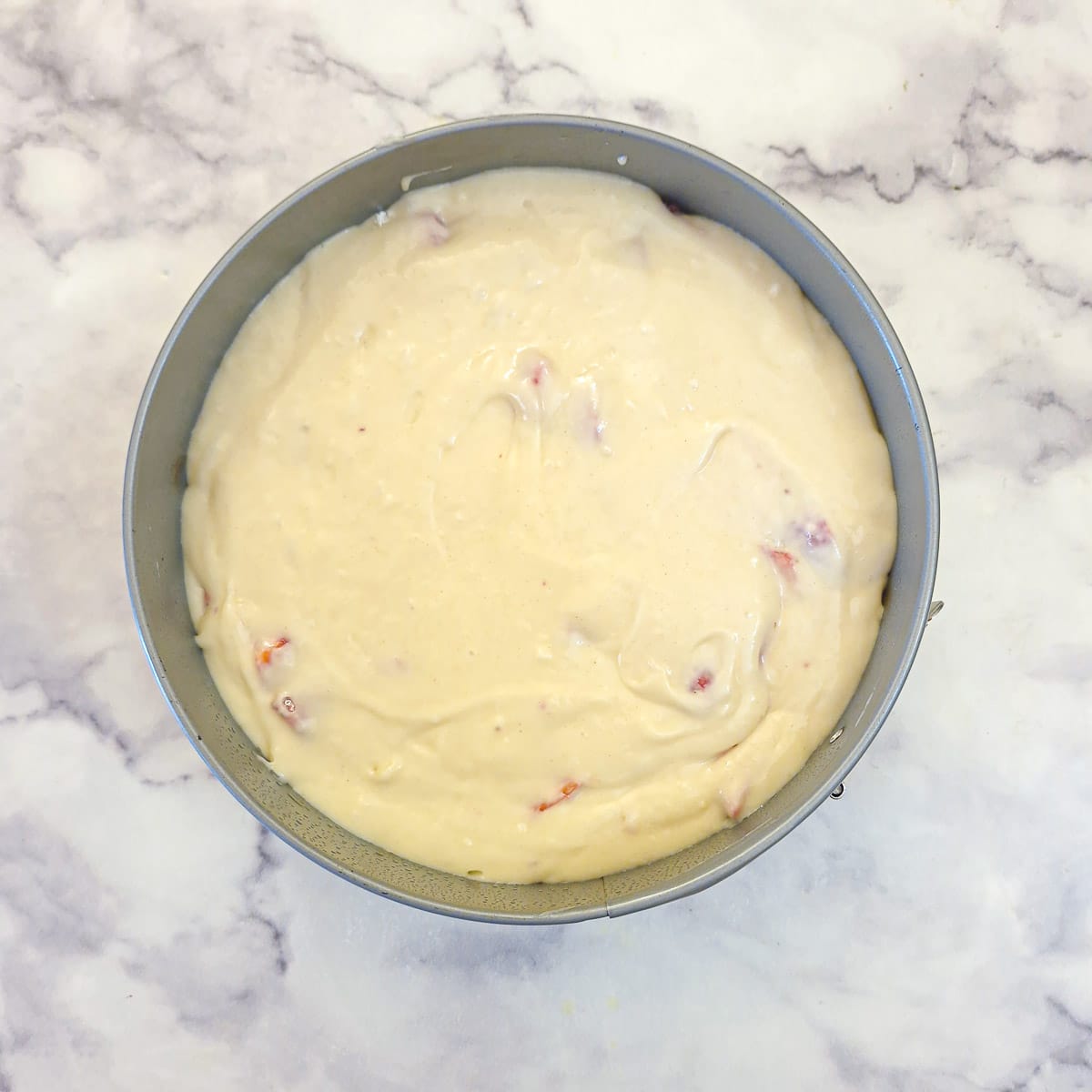 Raw strawberry cake batter poured into a round cake pan.