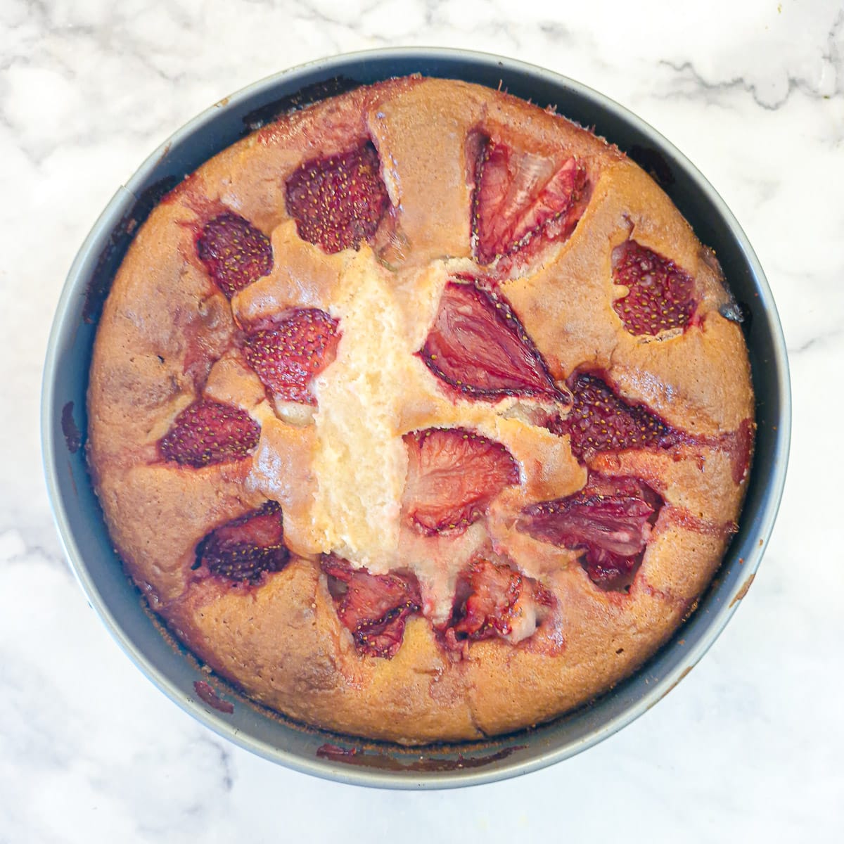 A baked strawberry cake in a round cake pan.