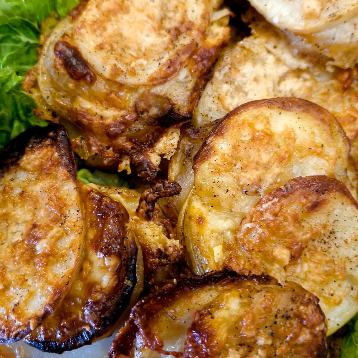 Close up of golden brown cheesy potato and onion slices.