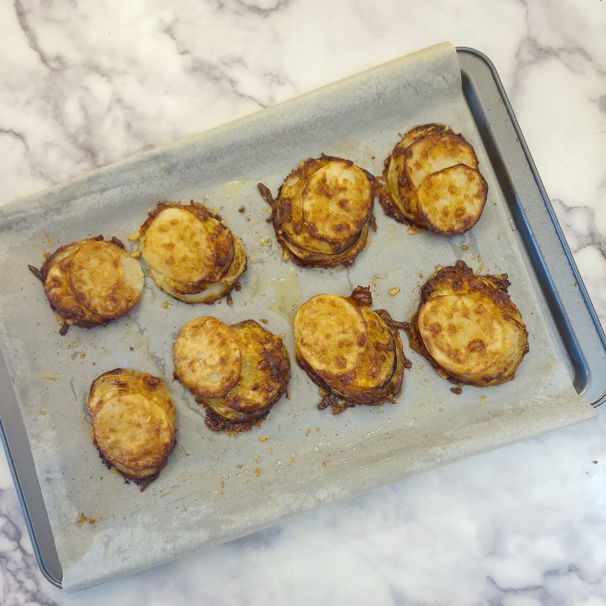 8 golden brown baked potato slices on a baking sheet.