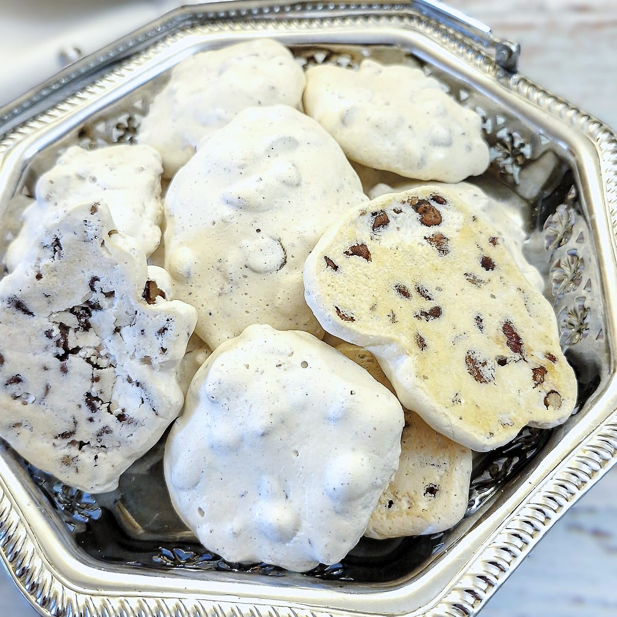 Close up of a mound of meringue nut cookies on a silver tray.