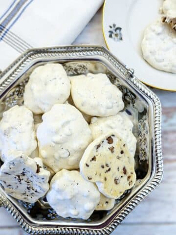 A slilver cake dish filled with choc chip meringue cookies.
