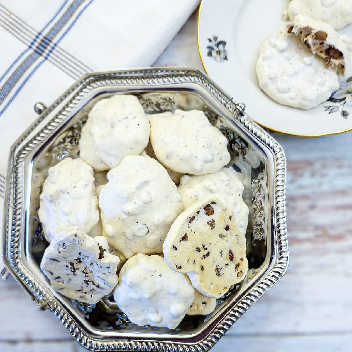 A slilver cake dish filled with choc chip meringue cookies.
