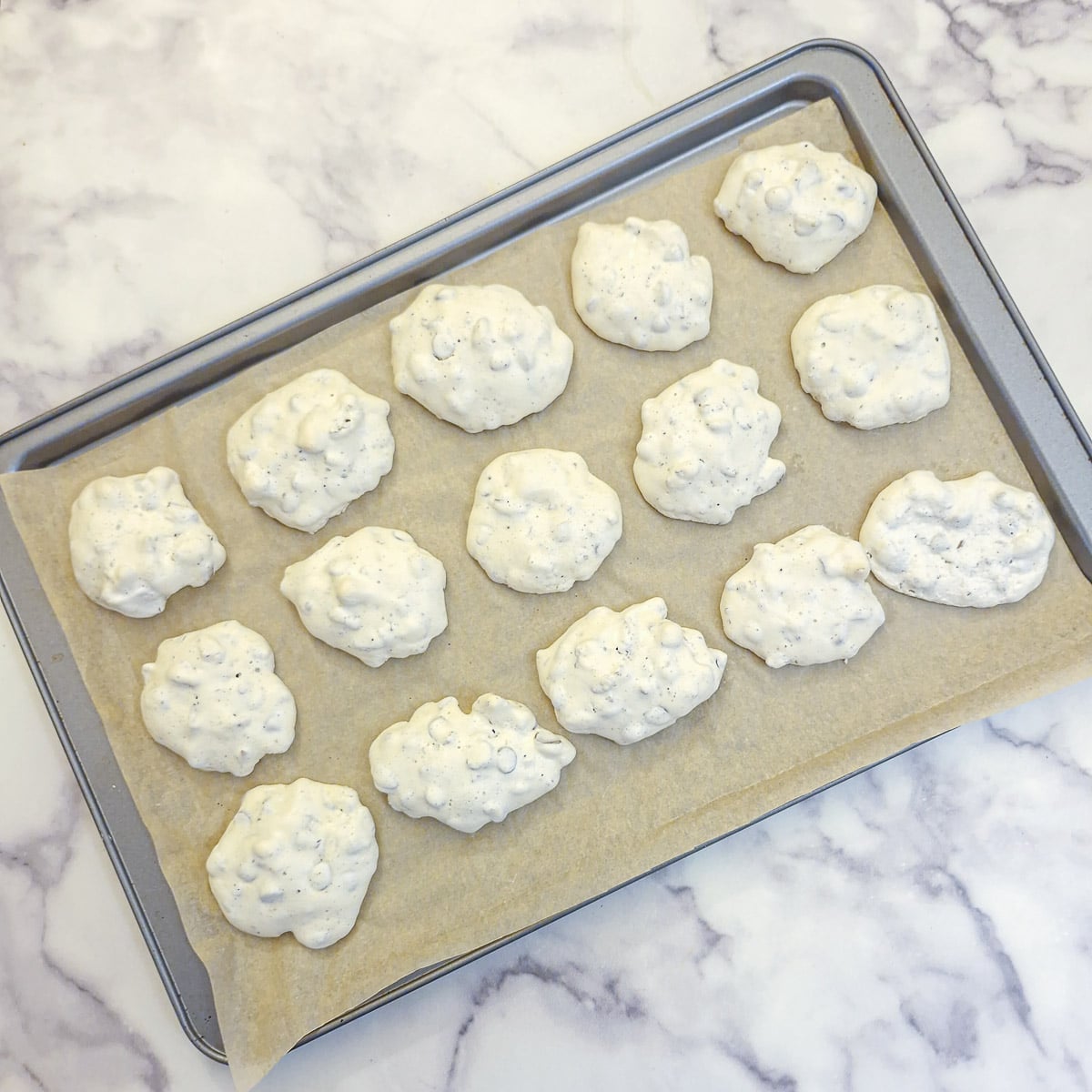 15 dried choc chip nut meringue cookies on a baking tray.