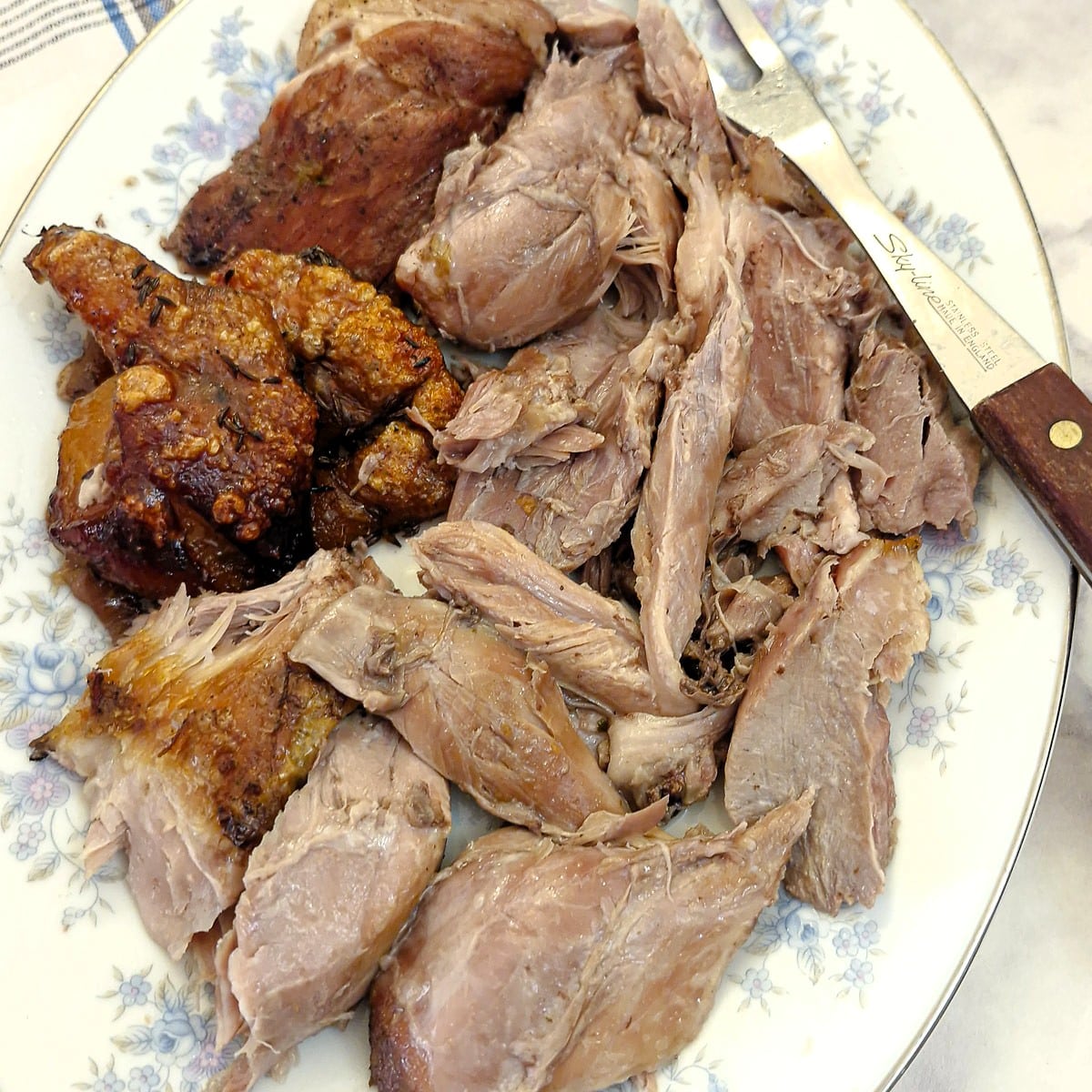 A pile of shredded pork pieces on a platter with crackling on the side.