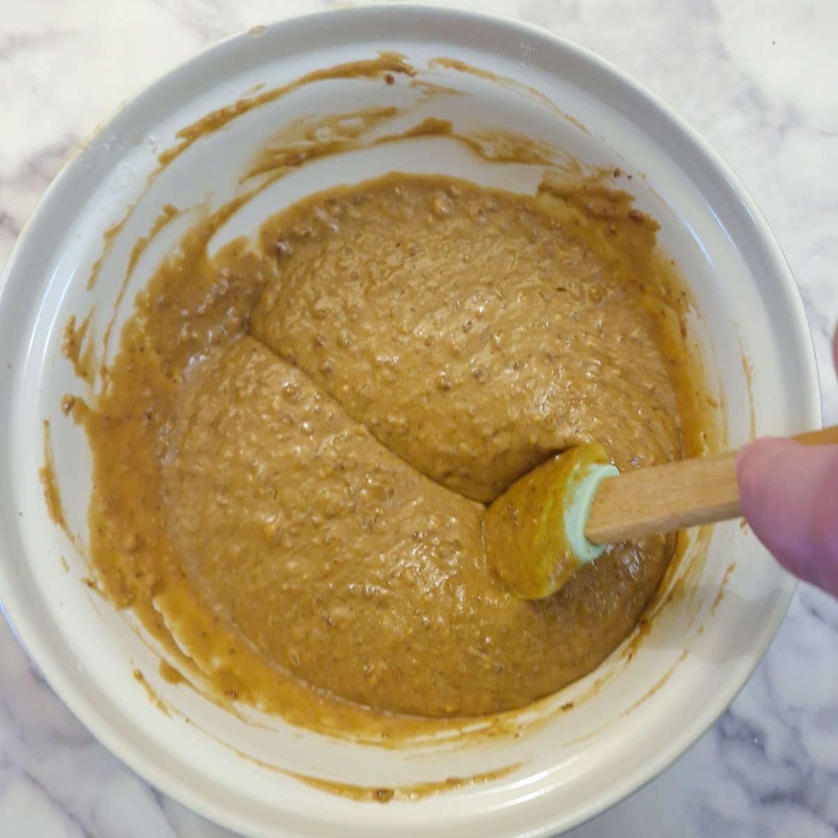 A spatula being drawn through the toffee pudding batter to show the consistency.