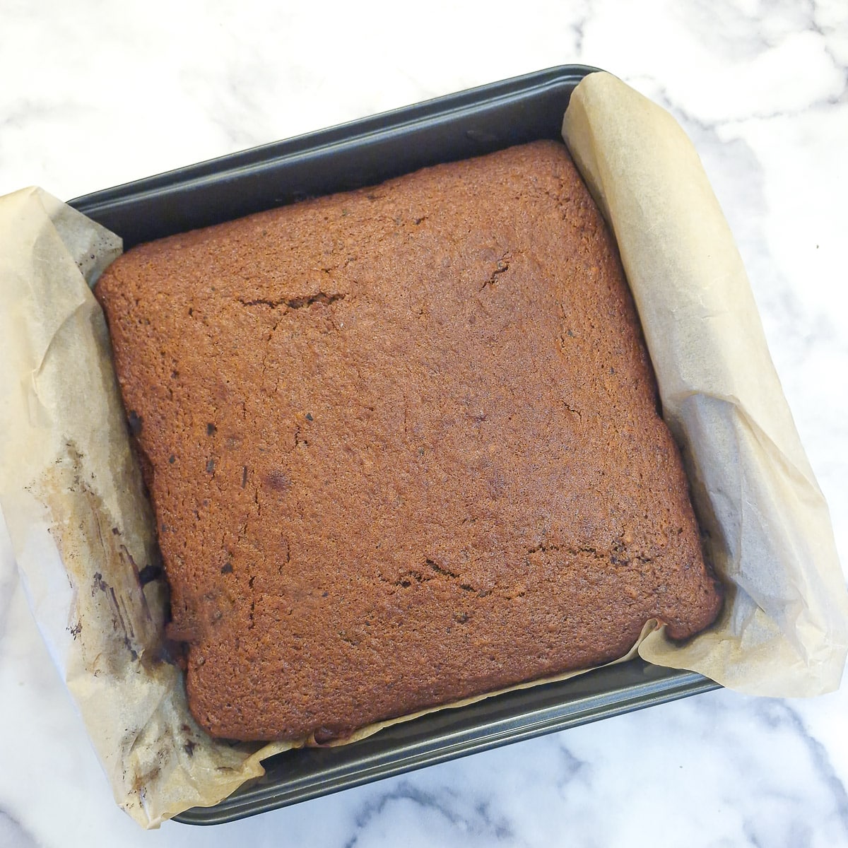 A baked toffee pudding traybake in a baking tin.