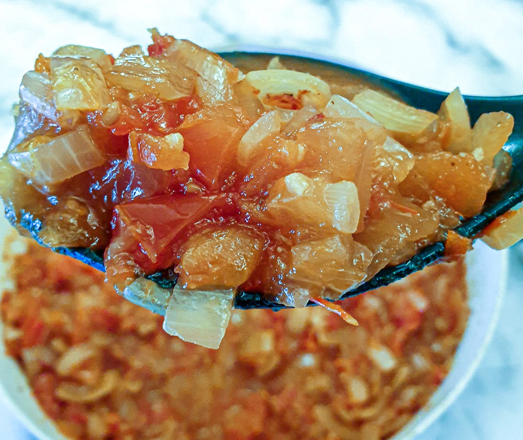Closeup of spoonful of spicy tomato and onion sauce.