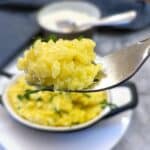 A forkful of risotto alla Milanese being lifted from a serving dish.