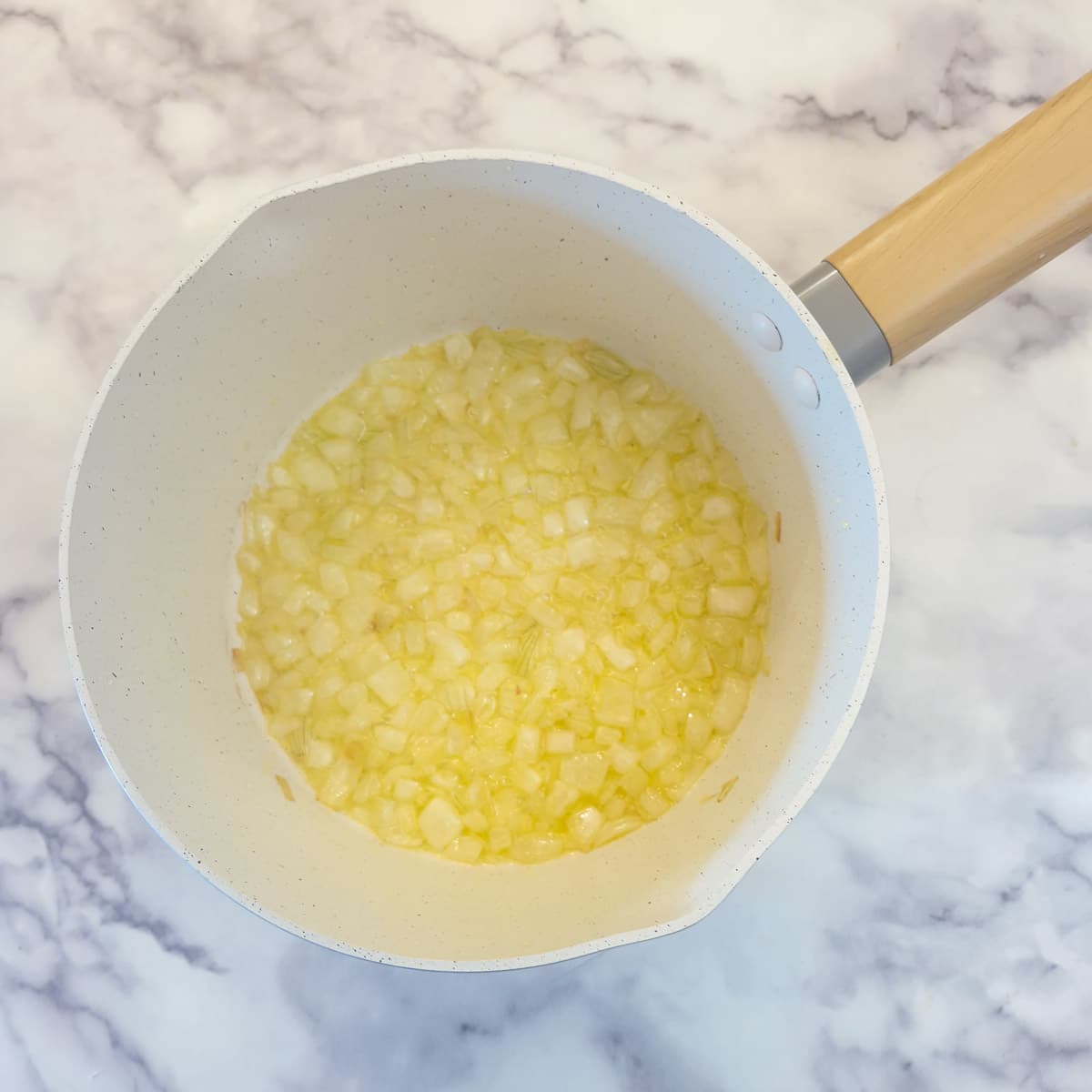 Onions softening in butter and olive oil in a saucepan.