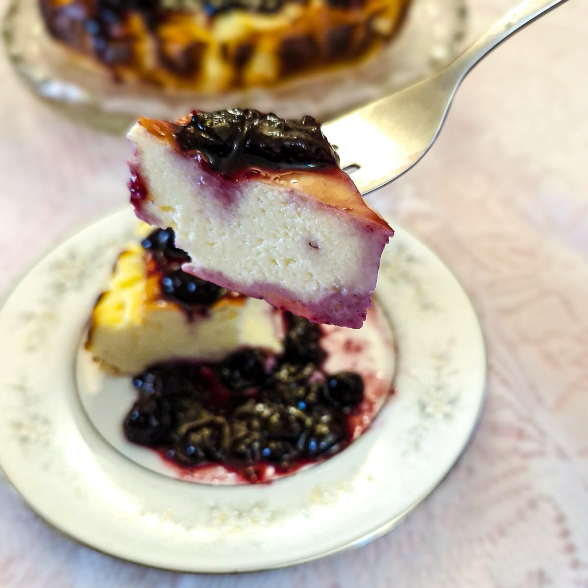 A forkful of yoghurt cheesecake with blueberry compote held above the plate.