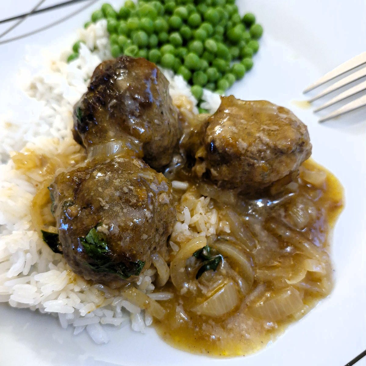 Three meatballs on a bed of rice smothered in chutney and onion gravy.