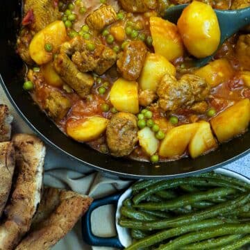 A dish of chicken aloo matar with Indian green beans in the foreground.