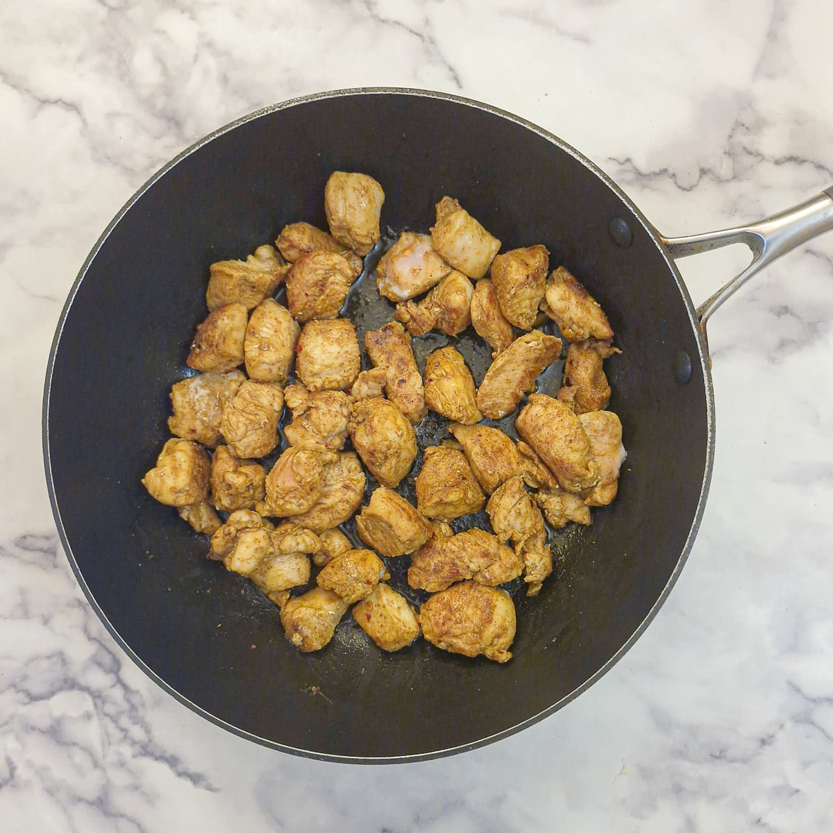 Step 2, chicken pieces searing in a frying pan.